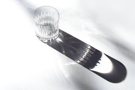 Trendy pattern made with glasses and shadows on gray white background. Sunlight through glass of water.の写真素材