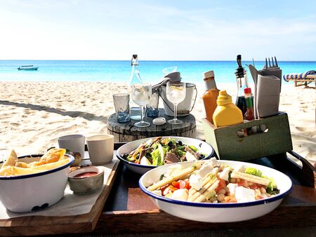 Lunch on the tropical beach on turquoise sea and sand background. Close up. Food summer concept.の写真素材