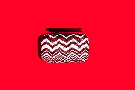 Valentines day, Christmas concept with stylish clutch bag clutch on classic red color backdrop. Trendy handbag with shadow. Copy space for text.の写真素材