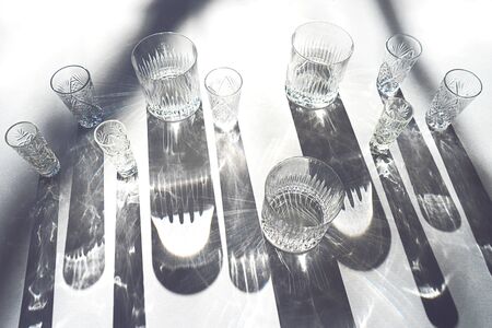 Trendy pattern made with glasses and shadows on gray white background. Sunlight through glass of water.の写真素材