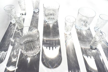 Trendy pattern made with glasses and shadows on gray white background. Sunlight through glass of water.の写真素材
