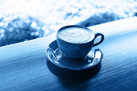 Color 2020 classic blue. Cup of coffee on tropical background, colored in blue.の写真素材