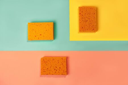 Trendy collage made of orange color sponges on yellow, pink coral and trendy mint green blue background. Flat lay, top view, close up. Minimal style.の写真素材