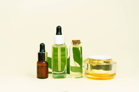 Various glass bottles with herbal CBD oil, THC tincture and hemp leaf on pastel beige background. Flat lay, minimal style. Cosmetics CBD oil. Essential natural oils for face and body.の写真素材