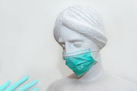 Head of sculpture of an antique woman in medical surgical mask and gloves as coronavirus preventionの写真素材