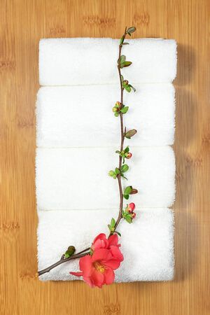 Beauty and spa concept. White towels and red flower on bamboo tray on marble background. Flat lay.の写真素材