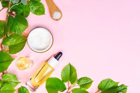 Skin care products, natural cosmetic. Flat lay image on pink background. Natural cosmetic skincare bottle, serum and organic green leaf. Homemade and beauty product concept.の写真素材