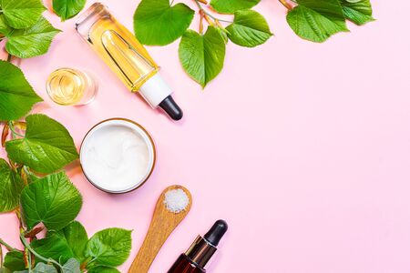 Skin care products, natural cosmetic. Flat lay image on pink background. Natural cosmetic skincare bottle, serum and organic green leaf. Homemade and beauty product concept.の写真素材