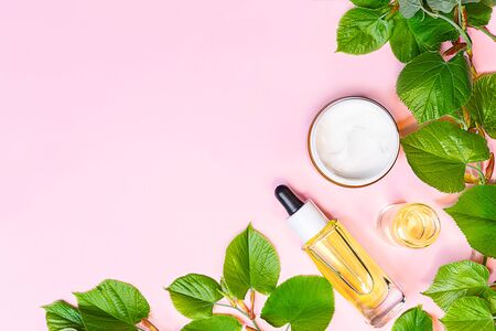 Skin care products, natural cosmetic. Flat lay image on pink background. Natural cosmetic skincare bottle, serum and organic green leaf. Homemade and beauty product concept.の写真素材