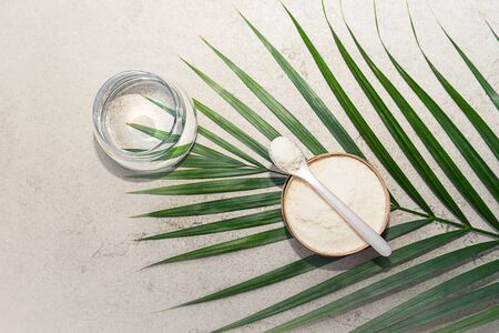 Closeup collagen with a spoon and glass of water on concrete background. Trendy healthy and beauty concept.の写真素材