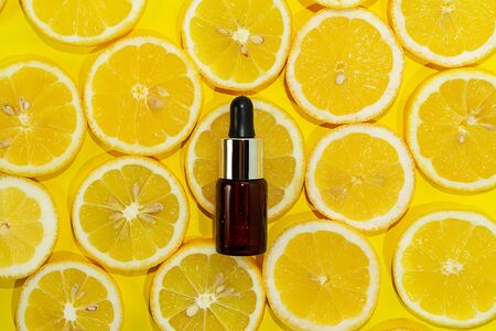 Natural vitamin c serum, skincare, essential oil product. Cosmetic with fresh juicy lemon fruit slice on lime background. Beauty product mock-up. Top view, flat layの写真素材