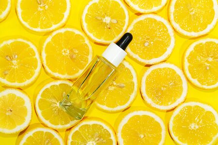 Natural vitamin c serum, skincare, essential oil product. Cosmetic with fresh juicy lemon fruit slice on lime background. Beauty product mock-up. Top view, flat layの写真素材