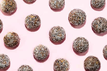 Pattern made of energy balls with oat, chocolate and coconut on pastel pink background. Healthy...