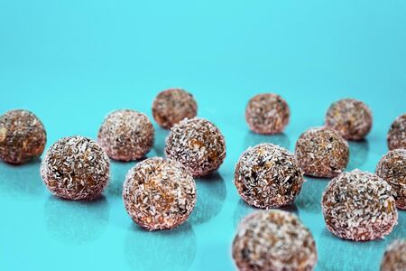 Energy balls with oat, chocolate and coconut on blue green mint background. Healthy vegan and raw food diet. Proper nutrition concept. Selective focus. Copy space.の写真素材