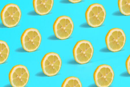 Pattern with lemon fruits. Tropical abstract lemon citrus wheel on green mint color background. Trendy summer pattern. Minimal fashion concept. Flat lay, close up.の写真素材