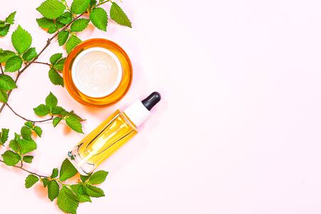 Skin care beauty products, natural cosmetic. Flat lay image on pink background. Natural cosmetic skincare bottle, serum and organic green leaf. Homemade and beauty product concept.の写真素材