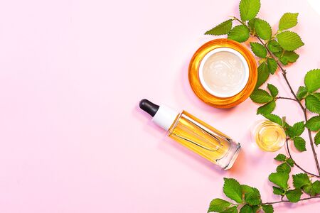 Skin care beauty products, natural cosmetic. Flat lay image on pink background. Natural cosmetic skincare bottle, serum and organic green leaf. Homemade and beauty product concept.の写真素材
