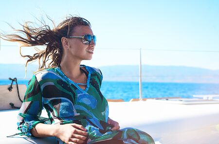 Young happy woman in sunglasses feels fun on the luxury sail boat yacht catamaran in turquoise sea...