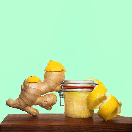 Ginger, lemon are ingredients of ginger water or tea prevents coronavirus on wooden board, on mint green color background. Alternative medicine. Traditional Indonesian, Asian drinks.の写真素材