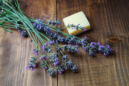 Spa massage setting with lavender flowers, soap on wooden background. SPA salon and beauty concept with warm light. Close up. Copy space.の写真素材