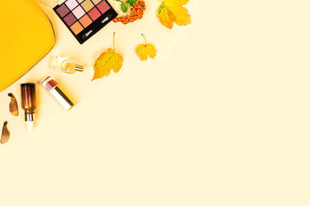 Flat lay and top view of beauty make up products and cosmetics set on autumn yellow leaves background with copyspace. Beauty concept for blogger.の写真素材