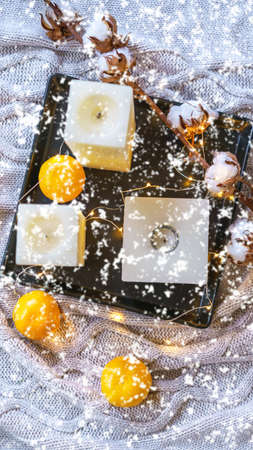 Flatlay Inspiration winter cozy still life composition with cotton, tangerines, candles and snowflakes on cozy gray plaid. Christmas card layout decoration idea. Flat lay, top view, copy spaceの写真素材