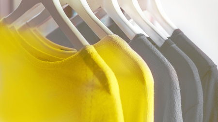 Bright illuminating yellow and gray colours clothes on hangers. Trendy colors of the year 2021 - Gray and Yellow. Fashionable clothes colors.の写真素材