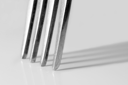 Tines of a fork with reflection on a glossy surface