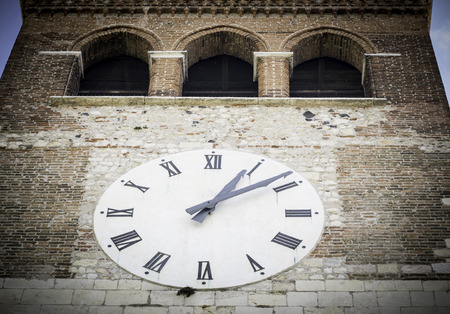 big white clock on the facade of the bell tower of a Romanesque abbey
