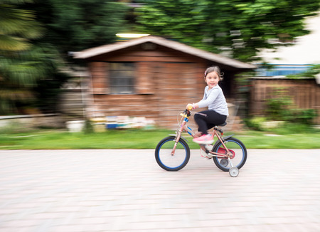 little girl ride fast on bike with castersの写真素材