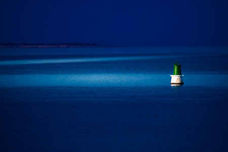 A buoy is reached at night by a patrol boat to be repaired.の写真素材
