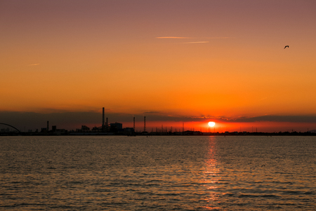 Sea sunset with silhouettes of a chemical industrial hub.の写真素材