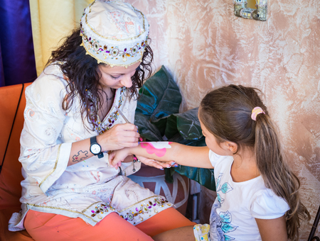 VERONA, ITALY - CIRCA SEPTEMBER 2015: Girl paints a washable tattoo on the arm of a child.のeditorial素材
