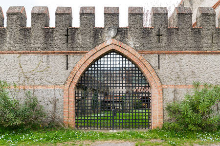 arched entrance of a medieval castle closed by an iron grille gate.のeditorial素材