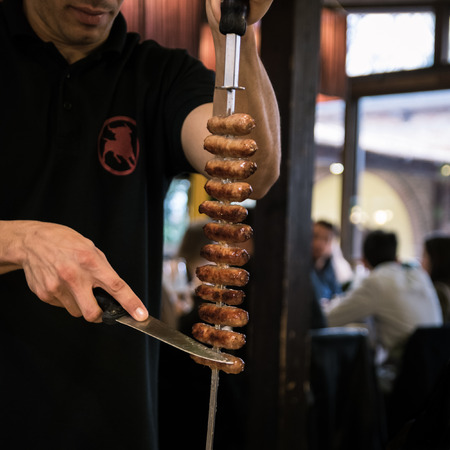 Meat skewered on a spit served to the table in a Brazilian restaurant.の写真素材