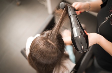 Detail of drying hair with hair dryer and brush at the hairdresser.の写真素材