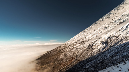 Mountain  partially covered with snow soars above the clouds.の写真素材