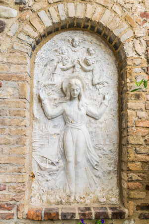 Bas relief surrounded by brick wall representing the Virgin Mary surrounded by angels.の写真素材