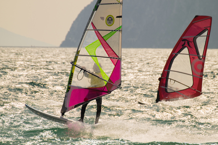 Windsurfing on Lake Garda surrounded by mountains, Italy.のeditorial素材