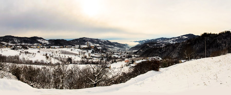 Panorama of a snowy meadow surrounded by mountains.
