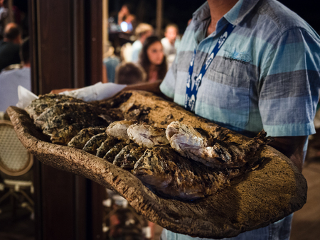 Grilled seabass served on cork tray at a seafood restaurant.のeditorial素材
