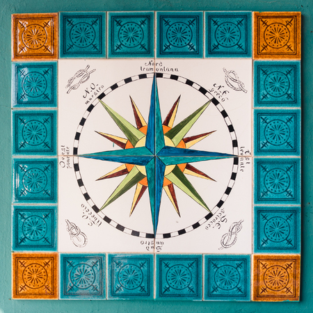 Sardinia, Italy - August 17, 2017: Rose of the winds and cardinal points painted on tiles in a...