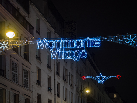 Illuminated sign with the words "Montmartre Village" placed at the beginning of the famous Montmartre district, Paris.のeditorial素材