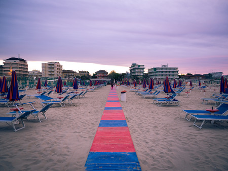 Red and blue plastic catwalk leading from the beach to the sea at sunset.のeditorial素材
