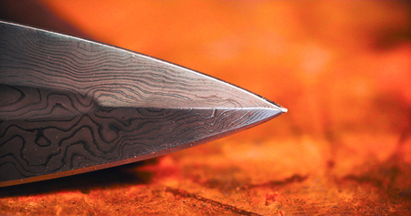 Detail of the tip of a medieval sword on red background.の写真素材