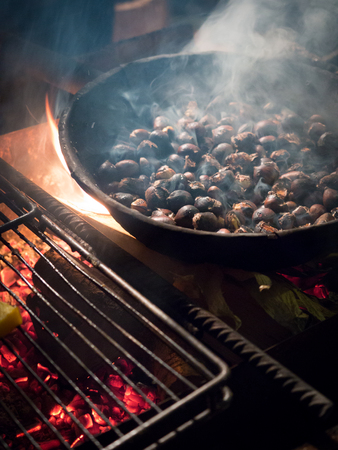 Pan-fried chestnuts cooked directly on the flame of an outdoor fire.の写真素材