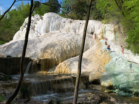 Bagni San Filippo, Italy - April 24, 2019: People rest on the thermal salt waterfalls of the mineral springs of Bagni San Filippo on a sunny day.のeditorial素材