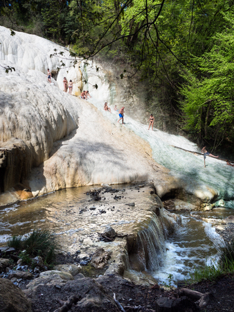 Bagni San Filippo, Italy - April 24, 2019: People rest on the thermal salt waterfalls of the mineral springs of Bagni San Filippo on a sunny day.のeditorial素材