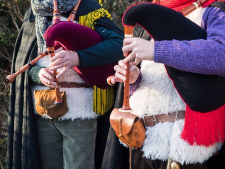 Bagpipe players in gowns during a traditional festival.