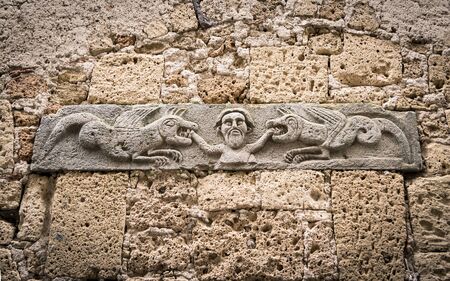 Stone bas-relief depicting a man being devoured by two dragons.